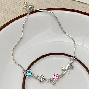 Silver bracelet with cat charm and colorful crystals on white ceramic plate display