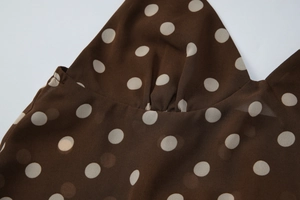 Gros plan sur le tissu en mousseline marron à pois blancs et détails plissés fins