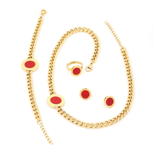 Flat lay of gold stainless steel jewelry set featuring circular red enamel accents