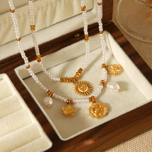 Detailed shot of golden sun flower charms and baroque pearls in a luxury wooden box