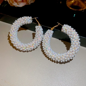 Macro detail of elegant hoop earrings with white pearls and iridescent rhinestones
