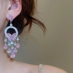 Macro detail of silver drop earrings featuring pink zirconia butterflies and tassels