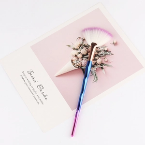 Macro shot of fan-shaped highlighter brush with gradient handle and rose gold ferrule