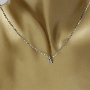 Collier argenté avec pendentif lettre A poli présenté sur un buste de mannequin