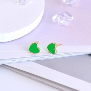 Detailed macro view of S925 silver heart stud earrings with green enamel and gold plating