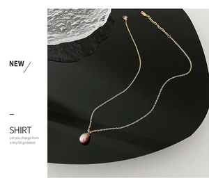 Detail of a natural champagne pearl pendant on a delicate gold titanium steel chain