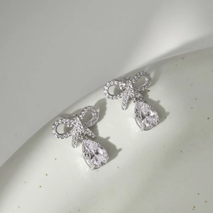 Detailed close-up of S925 silver bow stud earrings with pear-shaped zircon stones