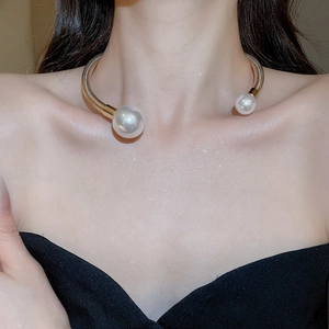 Detail of twisted gold choker with pearls on model featuring metallic texture and open design