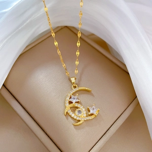 Detail of gold star and moon pendant necklace with clear gemstones on a soft fabric