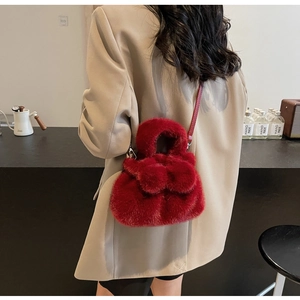 Detail of red plush bucket bag with leather strap styled on a neutral outfit