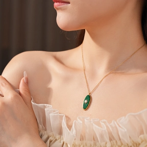 Close-up of vintage malachite sun oval pendant necklace with pearl on neck
