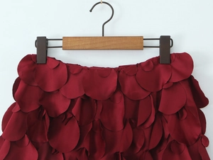 Vue détaillée d'une jupe bordeaux avec des couches de pétales et un tissu scintillant
