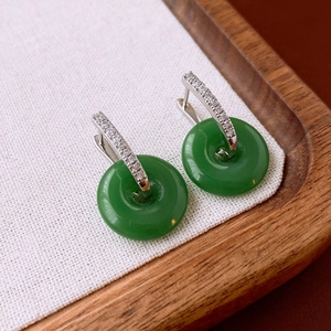 Macro shot of green jade donuts and silver earrings with sparkling zircon inlay details
