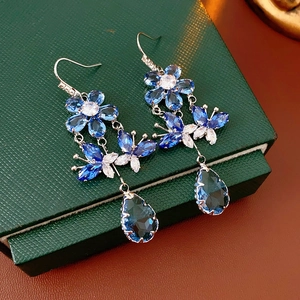 Close-up of blue crystal drop earrings with flower butterfly and silver zircon details