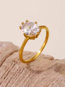 Macro shot of a gold oval zircon ring with prong setting on a natural rock background
