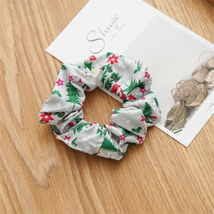 Detail of grey fabric scrunchie with Christmas tree pattern on a festive wooden surface