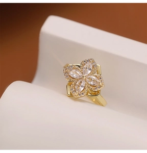 Macro shot of rotating gold flower ring with marquise-cut zircons on a white platform