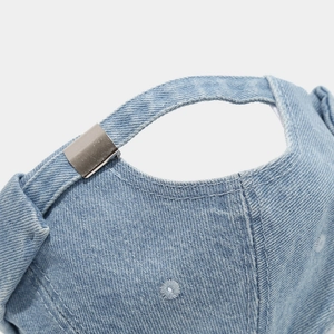 Close-up of adjustable metal buckle and embroidered eyelets on denim docker hat