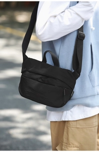 Close-up of black nylon crossbody bag with adjustable strap and zip pocket details