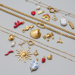 Detailed close-up of gold stainless steel DIY pendants with pearls and enamel motifs