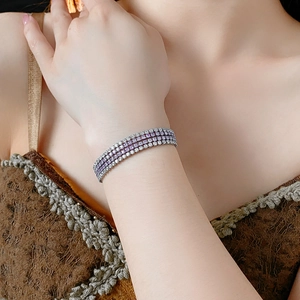 Gros plan d'un bracelet à trois rangées de zircons avec pierres violettes et blanches