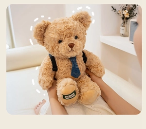 Close-up of cute plush teddy bear with a blue tie and small backpack accessory