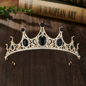 Close-up of golden crown with black oval gemstones and rhinestones on wood
