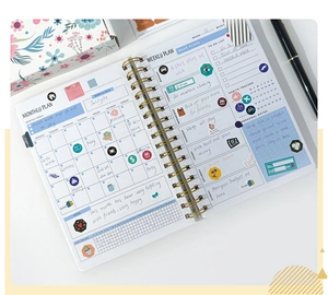 Open spiral planner showing monthly and weekly layouts with colorful stickers and handwritten notes