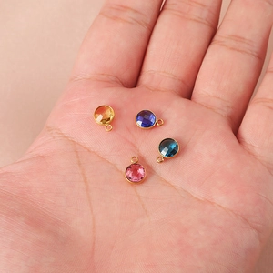 7mm gold-plated birthday stone charms for DIY necklaces held in a hand