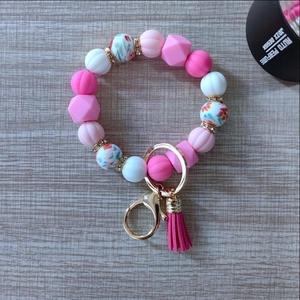 Macro detail of pink silicone beads, suede tassel, and golden hardware on key ring