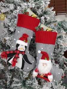 Close-up of penguin and Santa Claus Christmas stockings hanging on a snowy tree