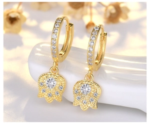 Macro shot of gold tulip earrings with sparkling cubic zirconia and floral pendant