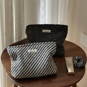 Close-up of woven polka dot cosmetic bags with simple wish label on a wooden table