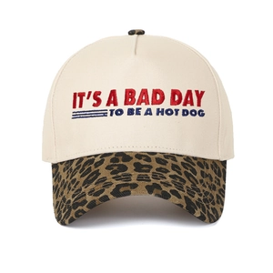 Detail of five-panel baseball cap with leopard print brim and red-blue text embroidery