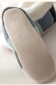 Detail of non-slip grippers on beige sole of striped knit winter floor socks