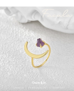 Detail of gold moon and star ring featuring natural purple amethyst stone on stone surface