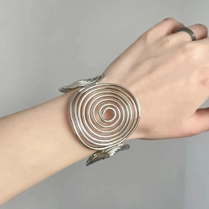 Polished silver spiral open bangle bracelet featuring a modern tiered metallic swirl design