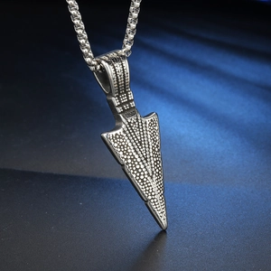 Macro view of silver arrow pendant with stippled texture on beaded stainless steel chain