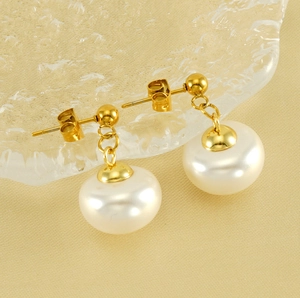 Détail de boucles d'oreilles vintage en perles dorées sur un plateau en verre texturé