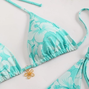 Detailed close-up of mint green floral bikini top with a decorative gold flower pendant