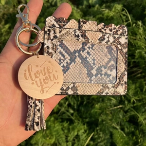 Close-up of snakeskin pattern card holder with tassel, gold hardware, and wooden charm