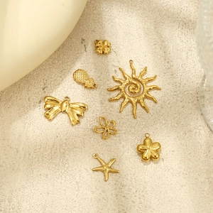 Detail view of golden metal DIY jewelry charms including sun, starfish and floral designs
