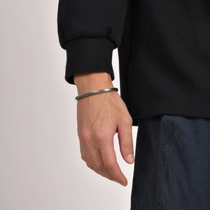Detail of vintage twisted stainless steel open bangle on a male wrist with silver finish
