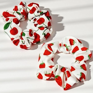 Détail de chouchous en tissu blanc avec motifs fraises et cerises sous une lumière douce