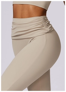 Detail view of high waisted flared yoga pants featuring ruched side waist design in apricot