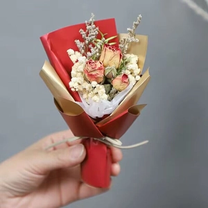 Close-up of a mini dried flower bouquet with red roses and white gypsophila