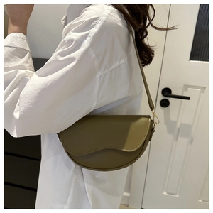Olive green saddle bag with wavy flap edge and gold hardware on white shirt model