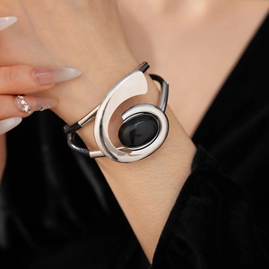 Detail view of retro silver metal and black leather woven bracelet with oval black stone