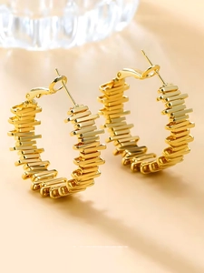 Macro shot of gold C-shaped twisted earrings with a unique textured geometric metal surface