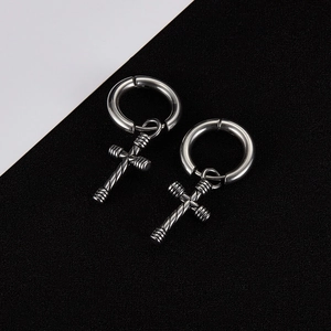 Macro shot of silver stainless steel hoop earring with a cross pendant on a split background